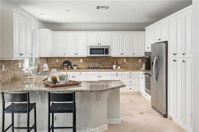 29125 Starwood Pl, Saugus, CA 91390 - kitchen featuring stainless steel appliances, a peninsula, white cabinets, light stone counters, and recessed lighting