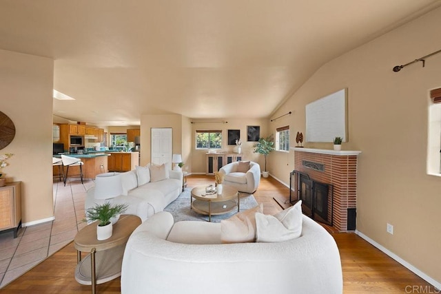 1153 Merritt Dr, El Cajon, CA 92020 - living room with a brick fireplace, vaulted ceiling, and light wood-type flooring