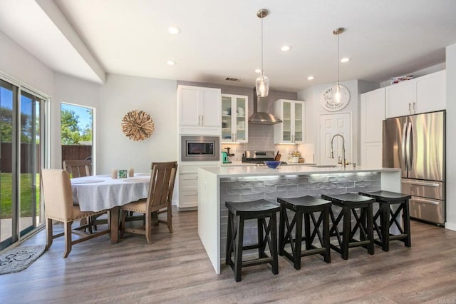 888 Arvita Ct, Oceanside, CA 92057 - kitchen with appliances with stainless steel finishes, backsplash, a large island with sink, wall chimney range hood, and a breakfast bar