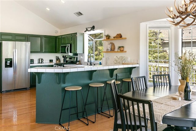915 Breithorn Dr, Lake Arrowhead, CA 92352 - kitchen with stainless steel appliances, green cabinets, tile counters, a breakfast bar area, and a chandelier