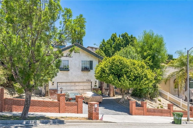 11922 Louise Ave, Granada Hills, CA 91344 - view of property hidden behind natural elements featuring a garage, stucco siding, and driveway