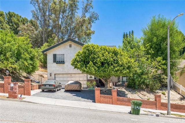 11922 Louise Ave, Granada Hills, CA 91344 - view of property hidden behind natural elements with a garage, driveway, and stucco siding
