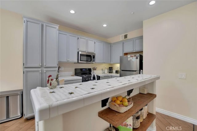 434 Sonora Cir, Redlands, CA 92373 - kitchen featuring stainless steel appliances, recessed lighting, light wood-style flooring, a kitchen bar, and tile counters