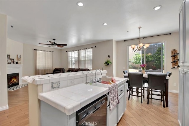 434 Sonora Cir, Redlands, CA 92373 - kitchen with tile countertops, dishwasher, open floor plan, light wood-type flooring, and recessed lighting