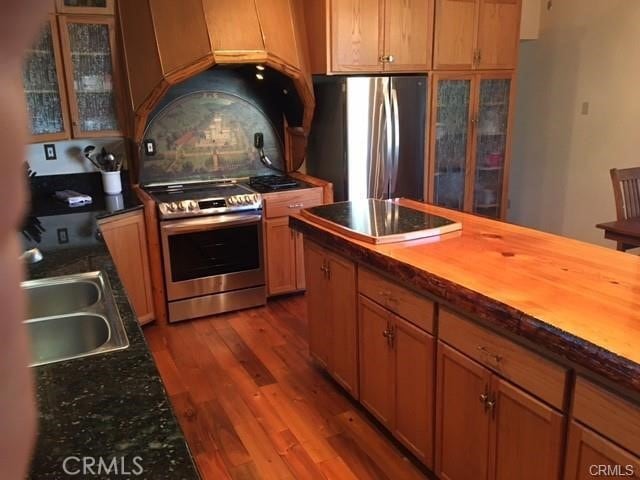 847 Tehama Dr, Big Bear Lake, CA 92315 - kitchen featuring appliances with stainless steel finishes, wood finished floors, backsplash, glass insert cabinets, and butcher block counters