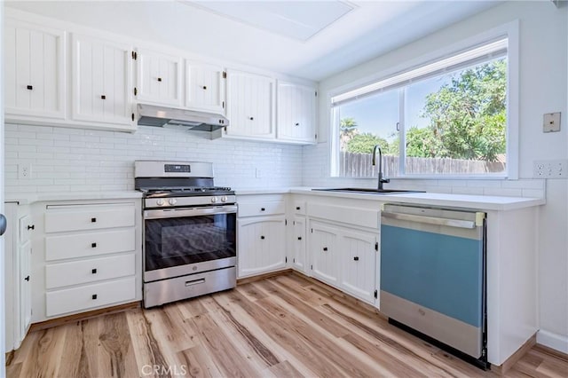 2950 Marie Ln, Merced, CA 95340 - kitchen with gas range, dishwashing machine, under cabinet range hood, decorative backsplash, and white cabinetry