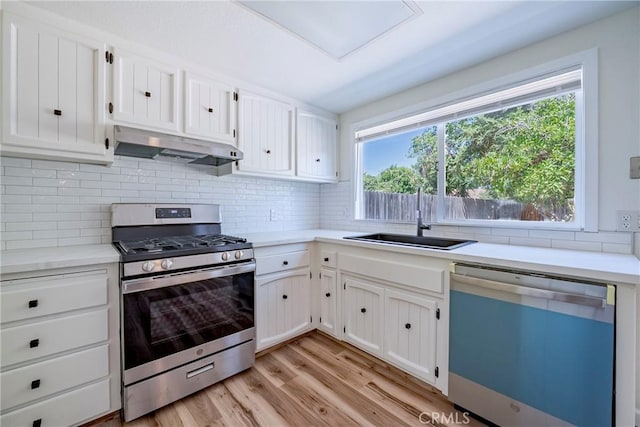 2950 Marie Ln, Merced, CA 95340 - kitchen with gas range, dishwashing machine, under cabinet range hood, light wood-type flooring, and decorative backsplash