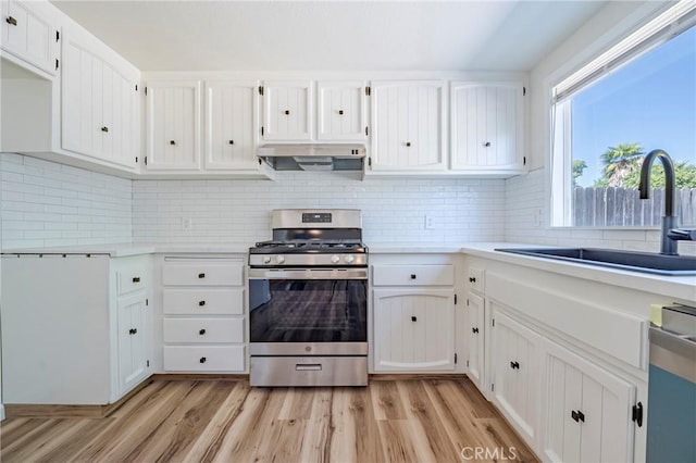 2950 Marie Ln, Merced, CA 95340 - kitchen featuring stainless steel range with gas stovetop, exhaust hood, light countertops, white cabinetry, and light wood-style floors