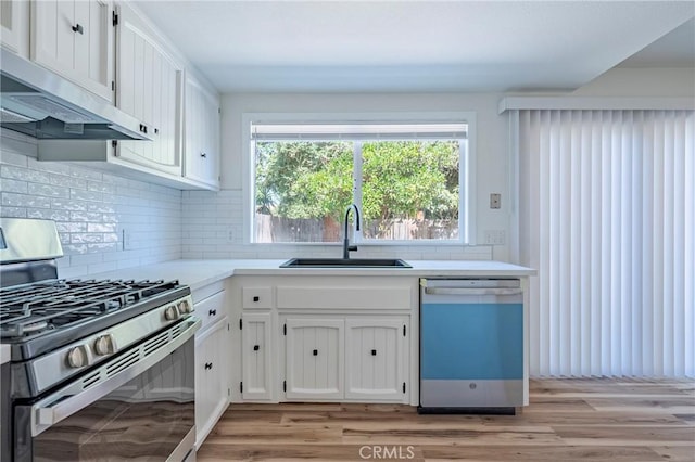 2950 Marie Ln, Merced, CA 95340 - kitchen featuring stainless steel gas stove, dishwasher, exhaust hood, white cabinetry, and tasteful backsplash