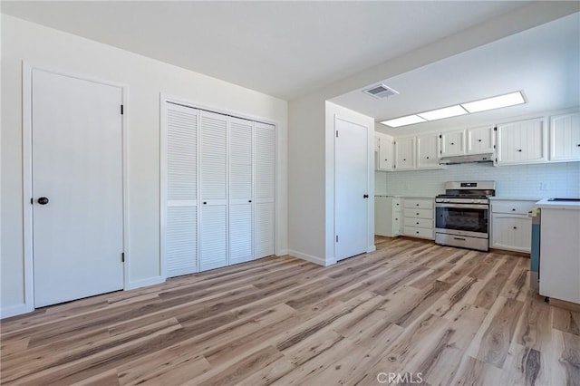 2950 Marie Ln, Merced, CA 95340 - kitchen featuring stainless steel stove, under cabinet range hood, light wood-style floors, light countertops, and white cabinetry