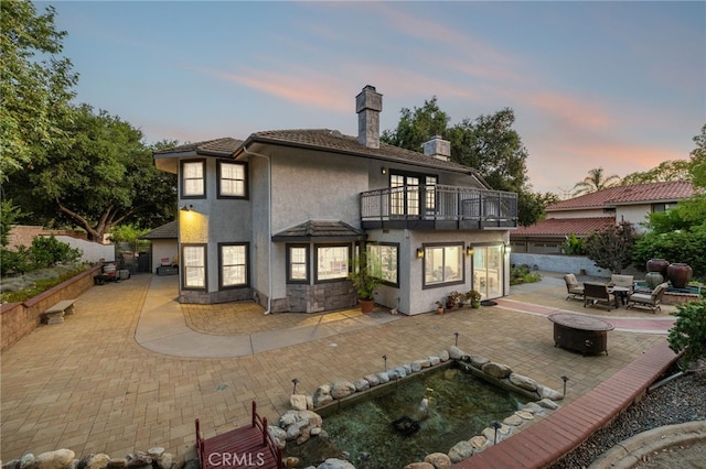 981 Deep Springs Dr, Claremont, CA 91711 - rear view of property featuring a balcony, an outdoor fire pit, a chimney, a patio, and stucco siding