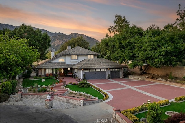 981 Deep Springs Dr, Claremont, CA 91711 - view of front facade with an attached garage, a mountain view, driveway, stucco siding, and a chimney