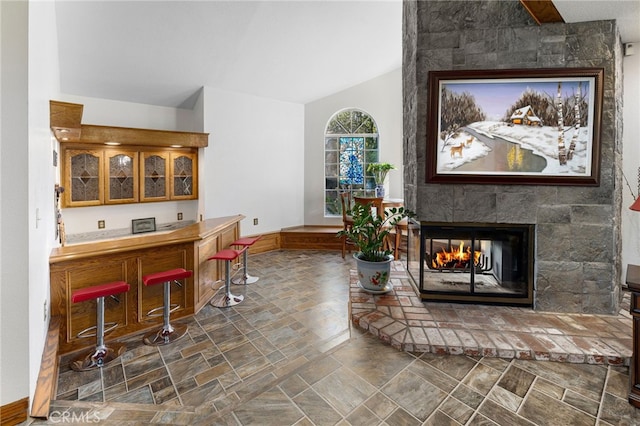981 Deep Springs Dr, Claremont, CA 91711 - living room featuring a multi sided fireplace, vaulted ceiling, stone finish flooring, and bar area
