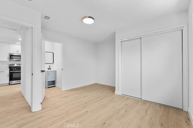 25415 Paloma Rd, San Bernardino, CA 92410 - unfurnished bedroom with light wood-type flooring, a closet, attic access, and connected bathroom