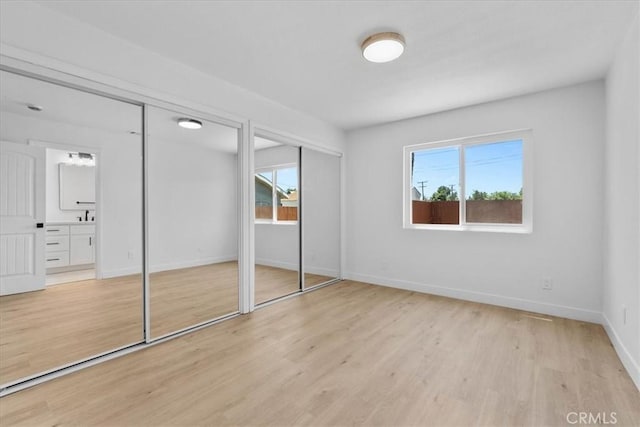 25415 Paloma Rd, San Bernardino, CA 92410 - unfurnished bedroom with two closets, multiple windows, light wood finished floors, and ensuite bath