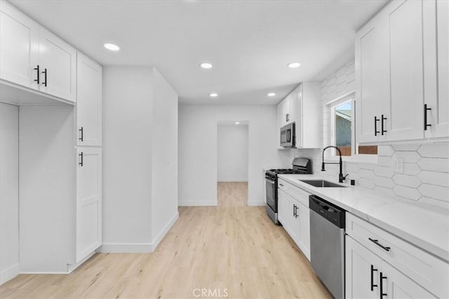 25415 Paloma Rd, San Bernardino, CA 92410 - kitchen featuring appliances with stainless steel finishes, light wood finished floors, backsplash, white cabinetry, and recessed lighting