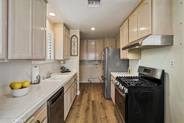 13239 Sayre St, Sylmar, CA 91342 - kitchen with stainless steel appliances, under cabinet range hood, tile countertops, wood finished floors, and light brown cabinets