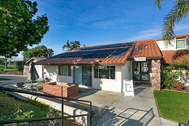 245 Fairlee Ln, Encinitas, CA 92024 - view of front of property featuring roof mounted solar panels, a tile roof, a patio area, and french doors