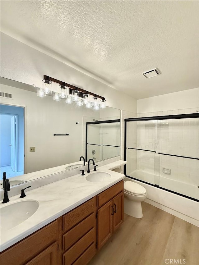 18 Decente, Irvine, CA 92614 - full bathroom featuring wood finished floors, a textured ceiling, double vanity, and bath / shower combo with glass door
