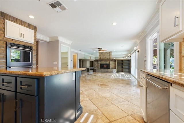 29 Hemingway Ct, Trabuco Canyon, CA 92679 - kitchen with stainless steel appliances, crown molding, ceiling fan, light stone counters, and white cabinetry