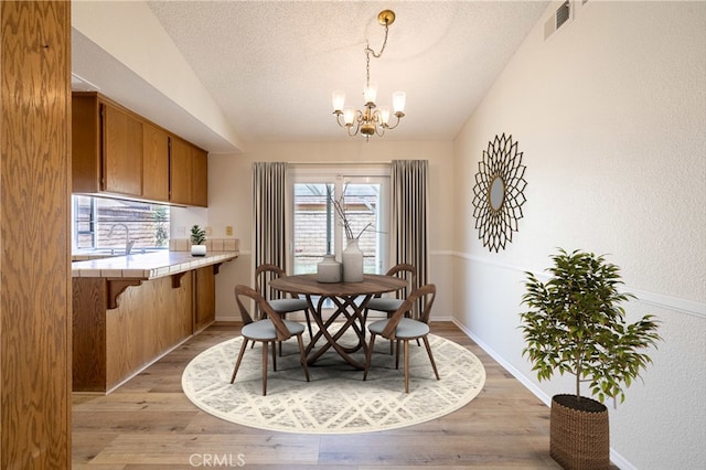43920 Delgado Ct, Lancaster, CA 93535 - dining room featuring vaulted ceiling, a chandelier, a textured ceiling, and light wood finished floors
