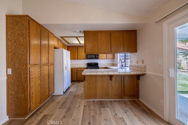 43920 Delgado Ct, Lancaster, CA 93535 - kitchen with white fridge with ice dispenser, black microwave, tile counters, brown cabinets, and a peninsula