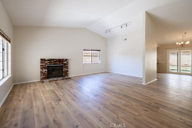 43920 Delgado Ct, Lancaster, CA 93535 - unfurnished living room featuring a chandelier, vaulted ceiling, plenty of natural light, wood finished floors, and a fireplace