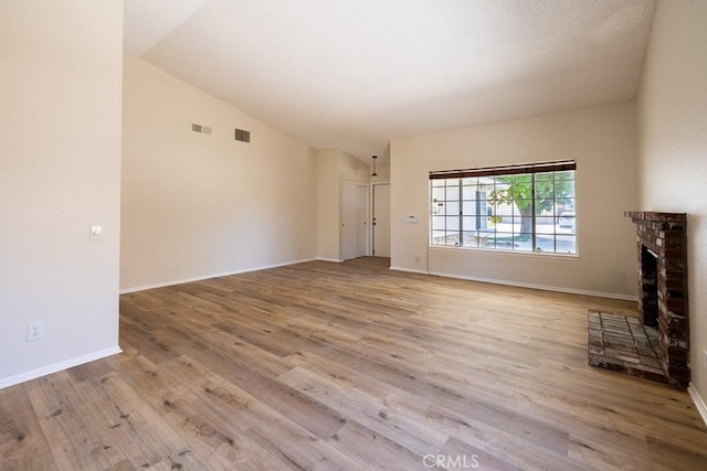 43920 Delgado Ct, Lancaster, CA 93535 - unfurnished living room featuring wood finished floors, a brick fireplace, and vaulted ceiling