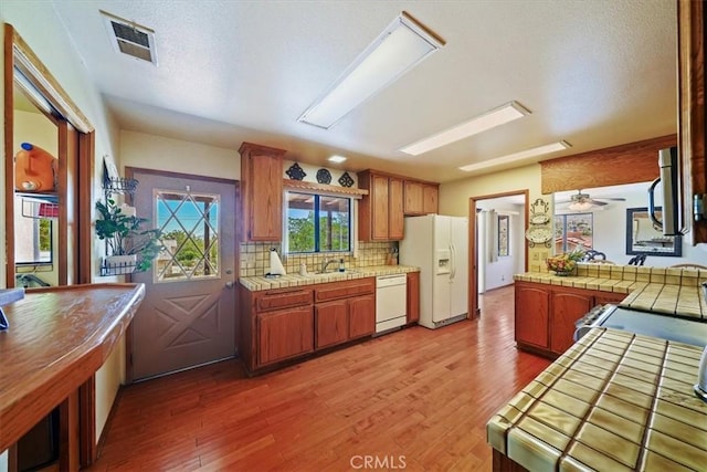 7575 Whitney Ave, Yucca Valley, CA 92284 - kitchen featuring white appliances, tile countertops, light wood-style flooring, and tasteful backsplash