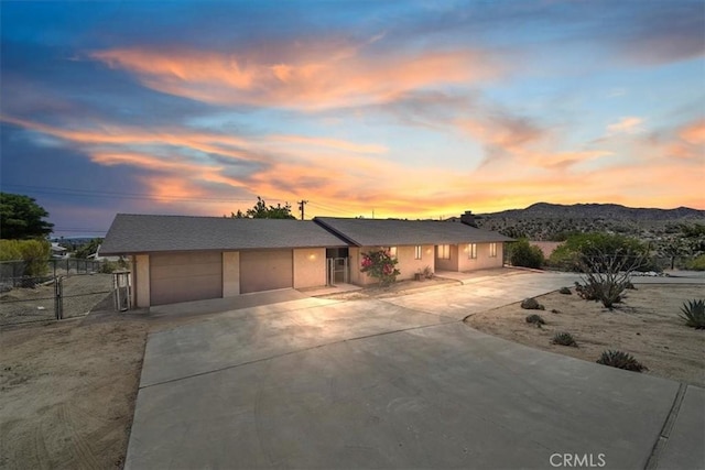 7575 Whitney Ave, Yucca Valley, CA 92284 - view of front of property featuring a garage, driveway, a mountain view, stucco siding, and a gate