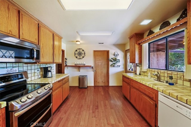 7575 Whitney Ave, Yucca Valley, CA 92284 - kitchen featuring appliances with stainless steel finishes, tile counters, tasteful backsplash, and wood finished floors