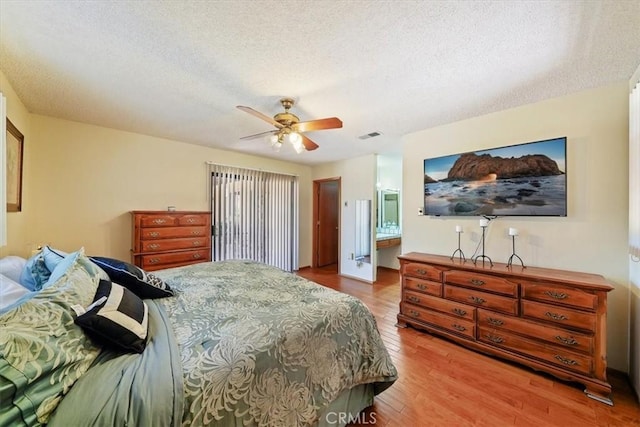 7575 Whitney Ave, Yucca Valley, CA 92284 - bedroom with wood finished floors, a textured ceiling, ceiling fan, and connected bathroom