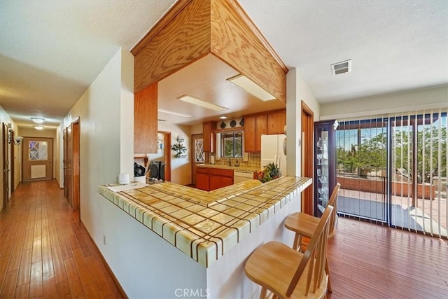 7575 Whitney Ave, Yucca Valley, CA 92284 - kitchen with white appliances, tile countertops, hardwood / wood-style floors, decorative backsplash, and a peninsula