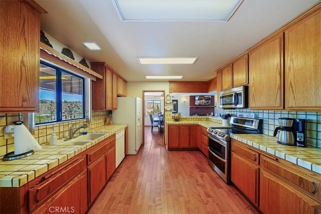 7575 Whitney Ave, Yucca Valley, CA 92284 - kitchen with stainless steel appliances, light wood-style floors, plenty of natural light, and decorative backsplash