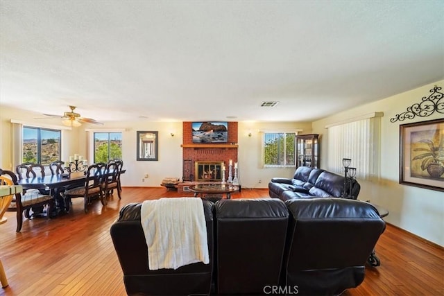 7575 Whitney Ave, Yucca Valley, CA 92284 - living area featuring light wood-style floors, a fireplace, and a ceiling fan