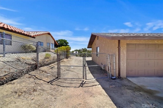 7575 Whitney Ave, Yucca Valley, CA 92284 - view of side of property featuring stucco siding, a gate, and a garage