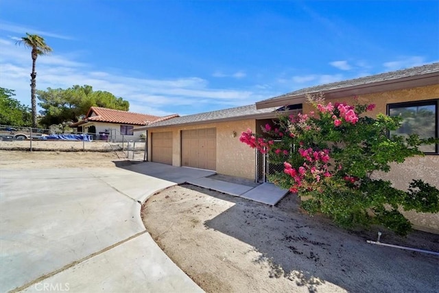 7575 Whitney Ave, Yucca Valley, CA 92284 - view of property exterior featuring driveway, stucco siding, and an attached garage