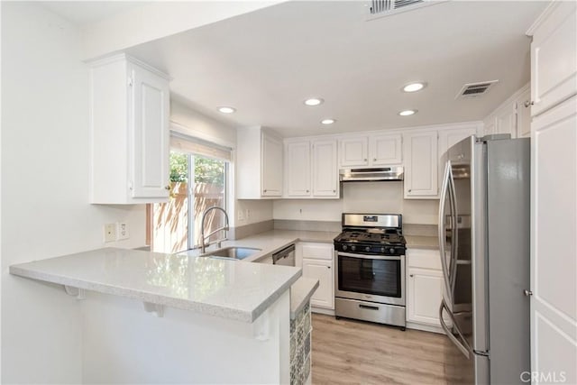 18 Rue Brittany, Lake Forest, CA 92610 - kitchen with appliances with stainless steel finishes, under cabinet range hood, a peninsula, recessed lighting, and white cabinetry