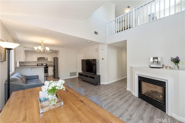 18 Rue Brittany, Lake Forest, CA 92610 - living room with a chandelier, light wood finished floors, a glass covered fireplace, and a high ceiling