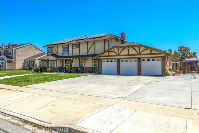 10735 Juniper Ave, Fontana, CA 92337 - tudor house featuring stucco siding, a garage, solar panels, and driveway