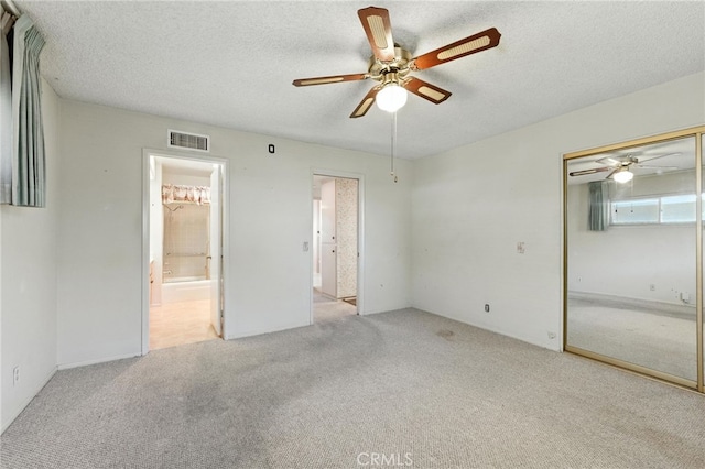 1181 Sandlewood Dr, Hemet, CA 92543 - unfurnished bedroom with carpet flooring, a textured ceiling, a closet, connected bathroom, and ceiling fan