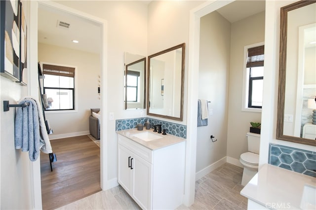 7051 Hurley Ct, San Bernardino, CA 92407 - bathroom with vanity, plenty of natural light, decorative backsplash, and wood finished floors