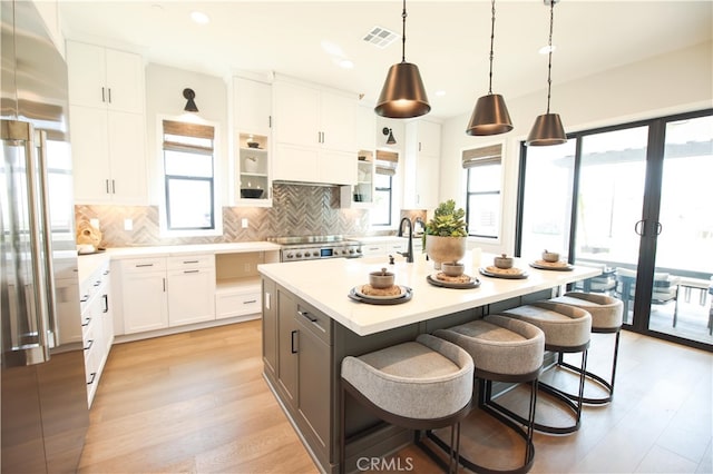 7051 Hurley Ct, San Bernardino, CA 92407 - kitchen with stainless steel built in fridge, a breakfast bar area, light countertops, backsplash, and stove