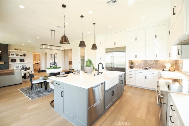 7051 Hurley Ct, San Bernardino, CA 92407 - kitchen with high end appliances, open floor plan, light wood-type flooring, light countertops, and white cabinets