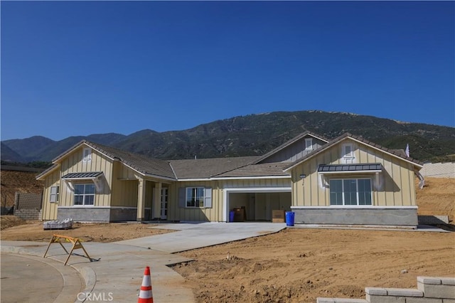 7051 Hurley Ct, San Bernardino, CA 92407 - view of front of property featuring board and batten siding, a mountain view, concrete driveway, and an attached garage
