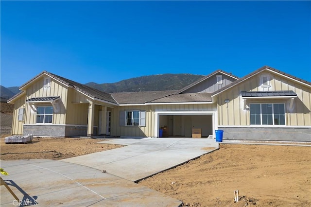 7051 Hurley Ct, San Bernardino, CA 92407 - view of front of property featuring board and batten siding, an attached garage, driveway, and a mountain view