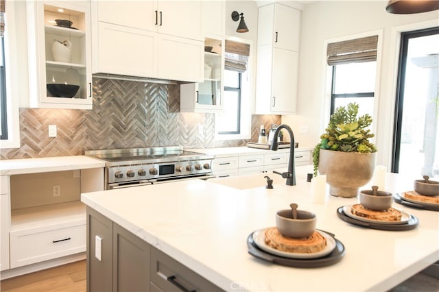 7051 Hurley Ct, San Bernardino, CA 92407 - kitchen with stainless steel stove, light countertops, glass insert cabinets, and white cabinets