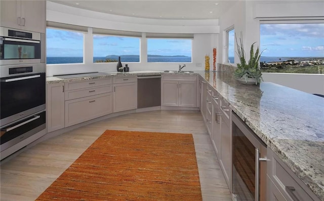 766 Pelican Dr, Laguna Beach, CA 92651 - kitchen featuring dishwasher, beverage cooler, a warming drawer, light wood-style flooring, and light stone counters