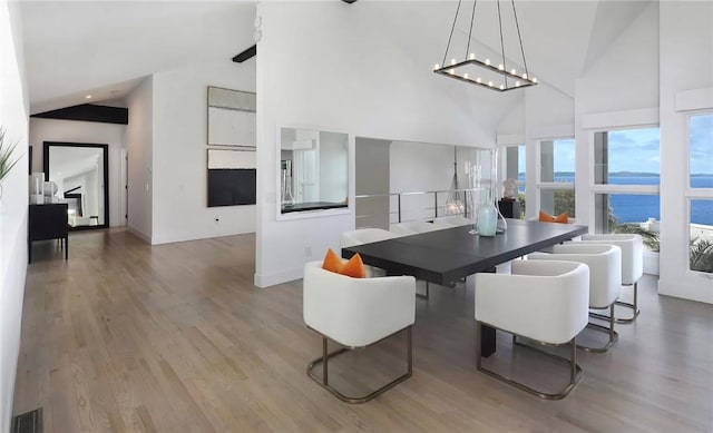766 Pelican Dr, Laguna Beach, CA 92651 - dining area with high vaulted ceiling, wood finished floors, a water view, and a chandelier