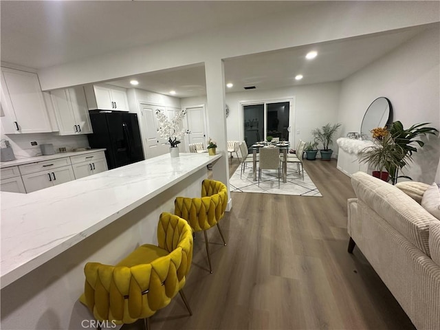 1598 W 7th St, San Bernardino, CA 92411 - kitchen featuring light stone counters, wood finished floors, black fridge with ice dispenser, white cabinets, and recessed lighting